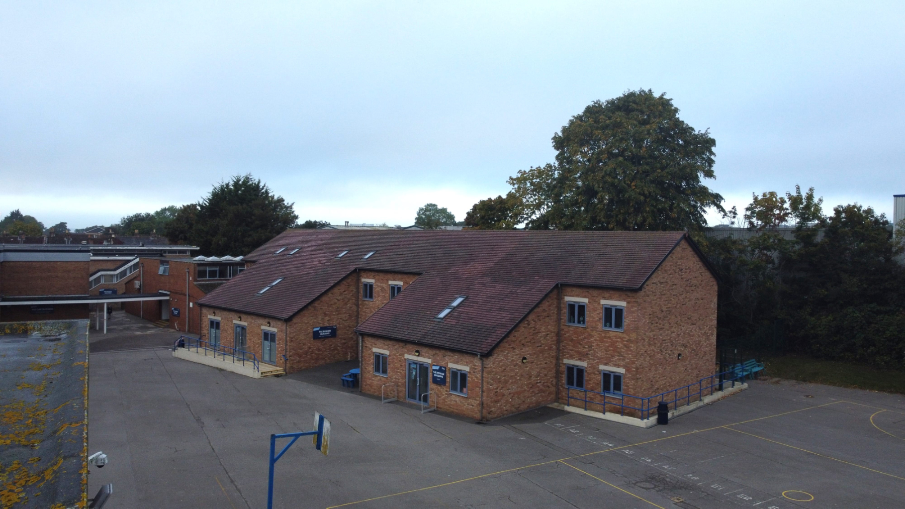Aerial drone view of a brick-built school building in Shirley, Southampton and playground area, showing the main entrance, surrounding hardstanding and nearby trees.