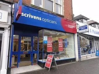 External view of Scrivens Opticians and Hearing Care old signage high street retail unit, showing shopfront frontage, signage and customer entrance within a commercial parade.