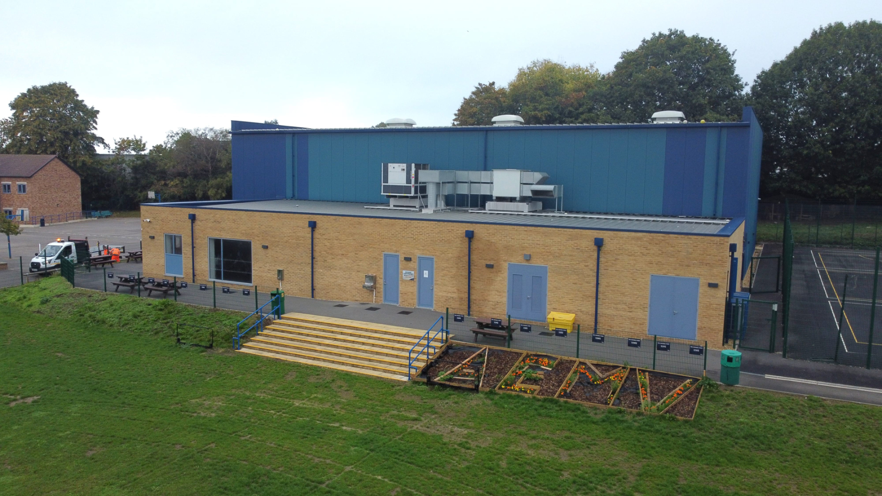 Aerial drone view of a school sports facility Aerial drone view of a school sports facility showing a sports hall building, outdoor multi-use games area, football pitch and surrounding school grounds.