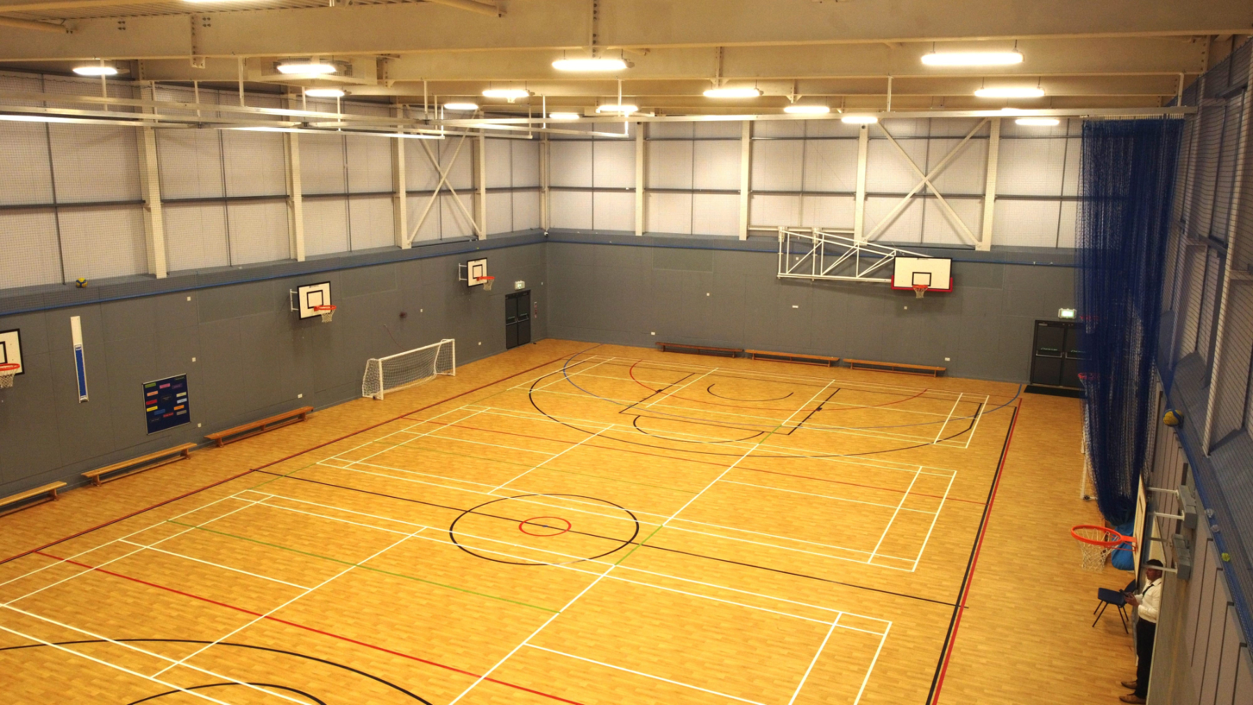 Interior view of a school sports hall with multi-use court markings, basketball hoops, indoor football goal and timber sports flooring, Shirley Southampton Hampshire