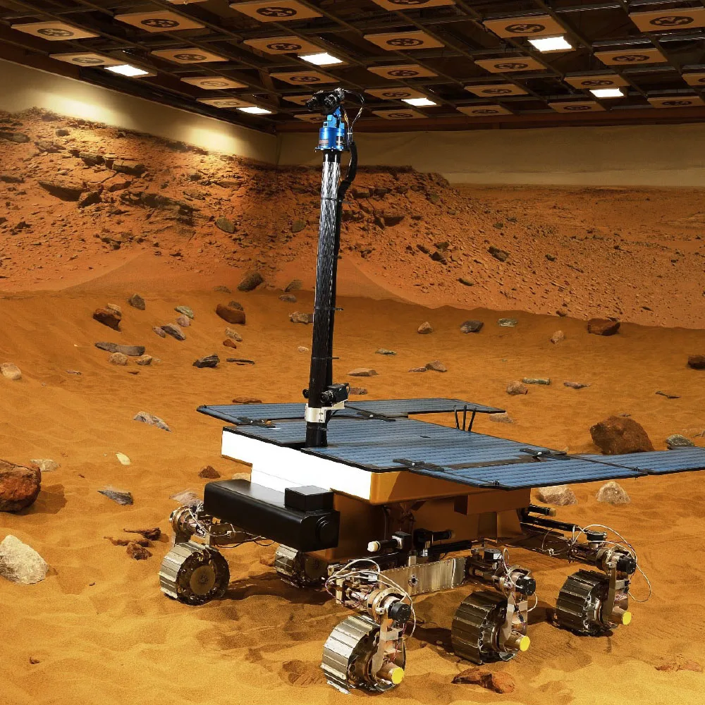 Internal view of a Mars yard testing environment featuring robotic rover prototypes on simulated planetary terrain within a controlled research and development facility