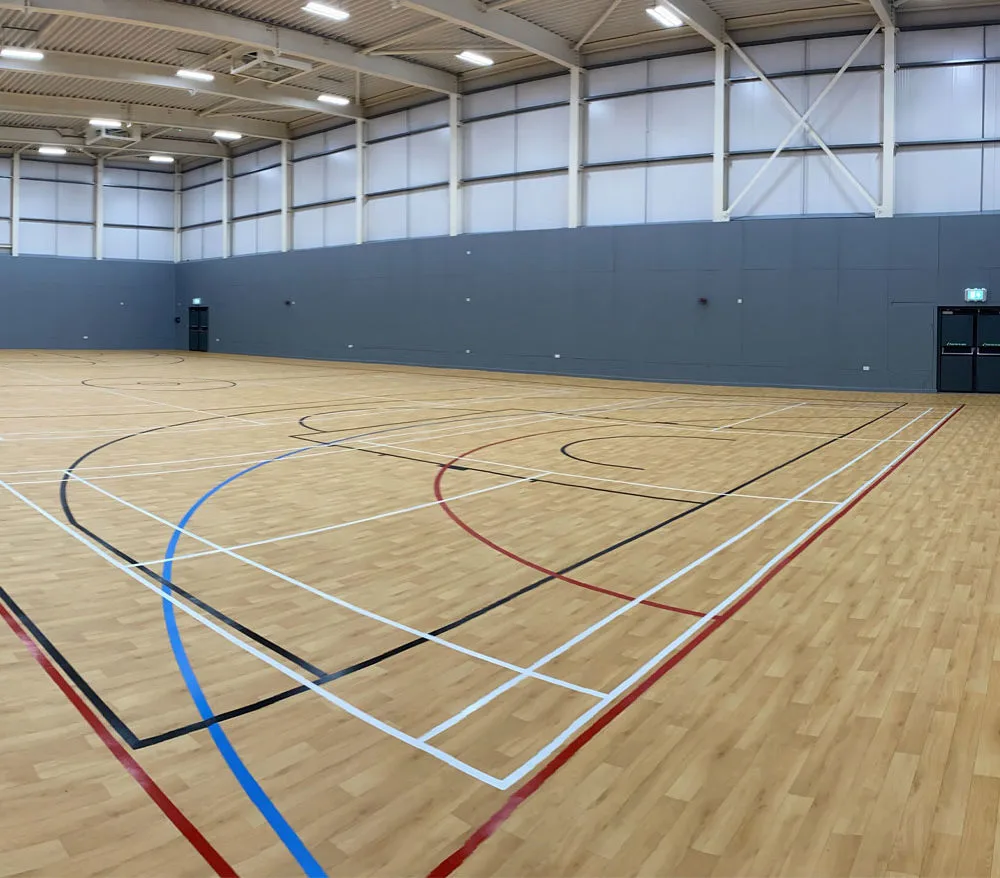 Completed indoor sports hall featuring multi-purpose court markings, timber sports flooring and high-level lighting within a modern leisure facility at Upper Shirley High School Southampton