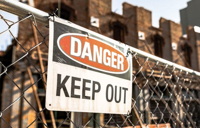 Danger Keep Out warning sign attached to fencing in front of a construction or demolition site.