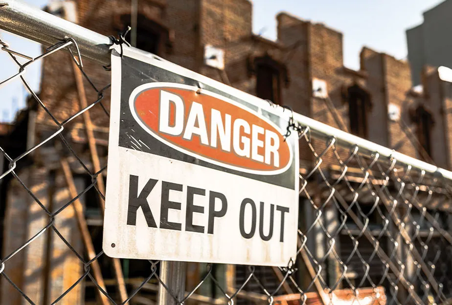 Danger Keep Out warning sign attached to fencing in front of a construction or demolition site.