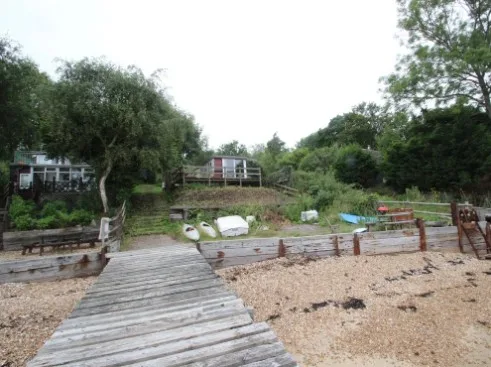 Site view showing stepped access path leading to waterfront property and shoreline, illustrating site topography and access conditions for residential development assessment