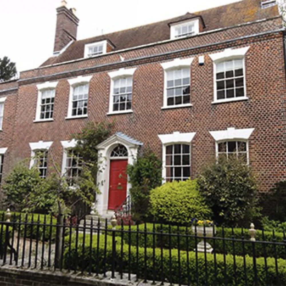 Exterior view of St James House in Poole, a traditional Georgian-style brick property with sash windows, red front door and landscaped garden frontage