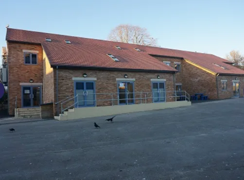 Aerial drone view of a brick-built school building and playground area, showing the main entrance, surrounding hardstanding and nearby trees, Southampton Hampshire