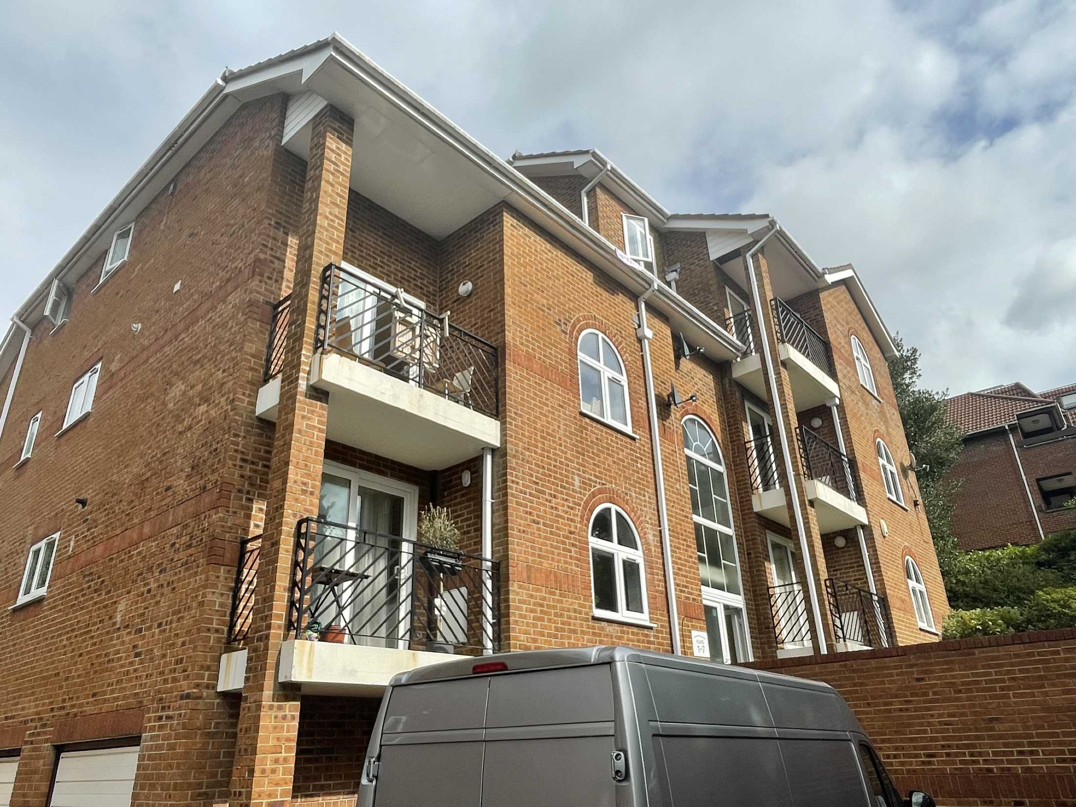 Exterior of modern brick apartment building with balconies viewed during residential building inspection in Poole, Dorset