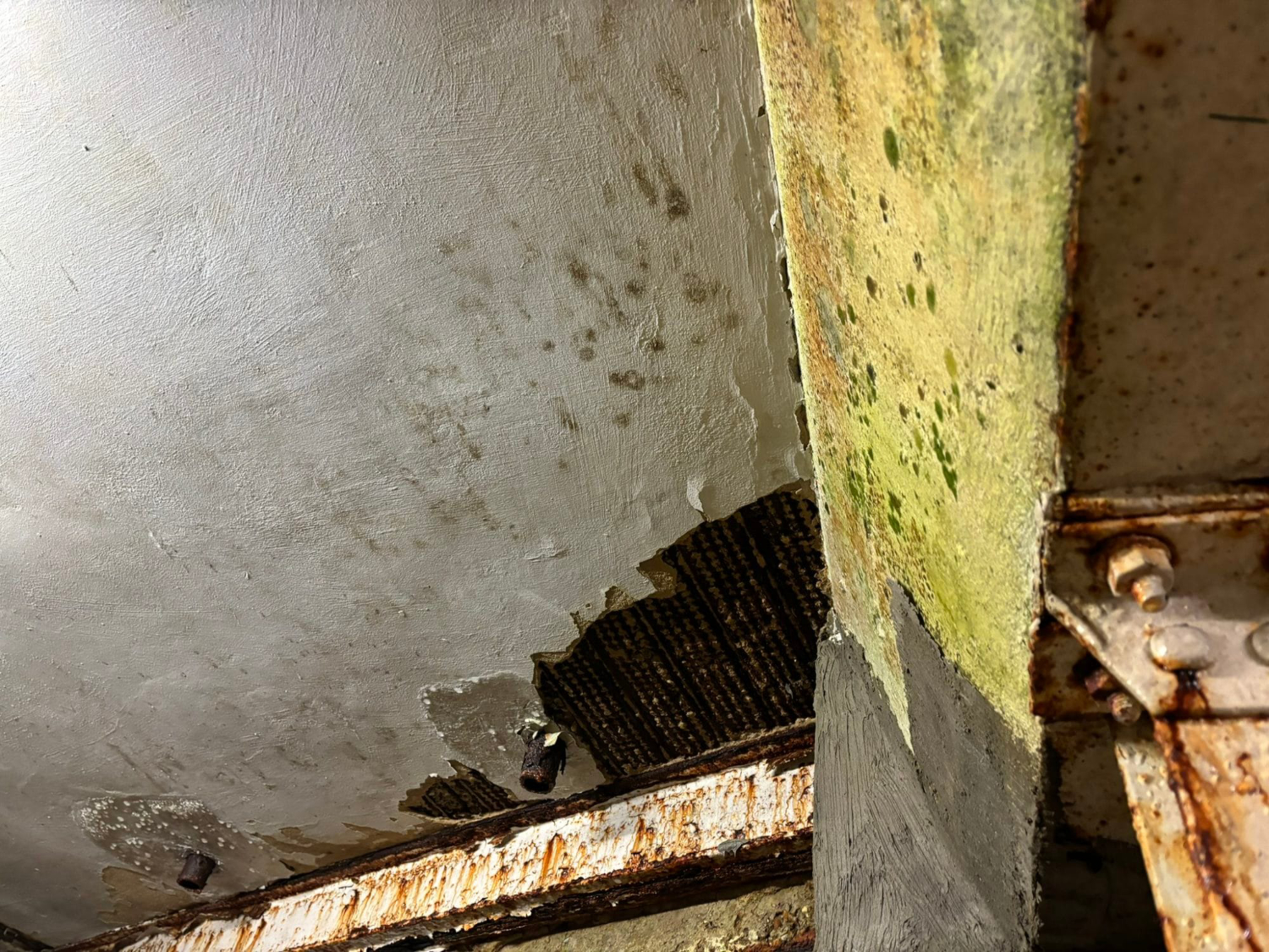 Water damage and damp staining to internal wall with peeling plaster and corrosion to structural steel beam. Dilapidations assessment at Lloyds Bank Shirley, Southampton, Hampshire