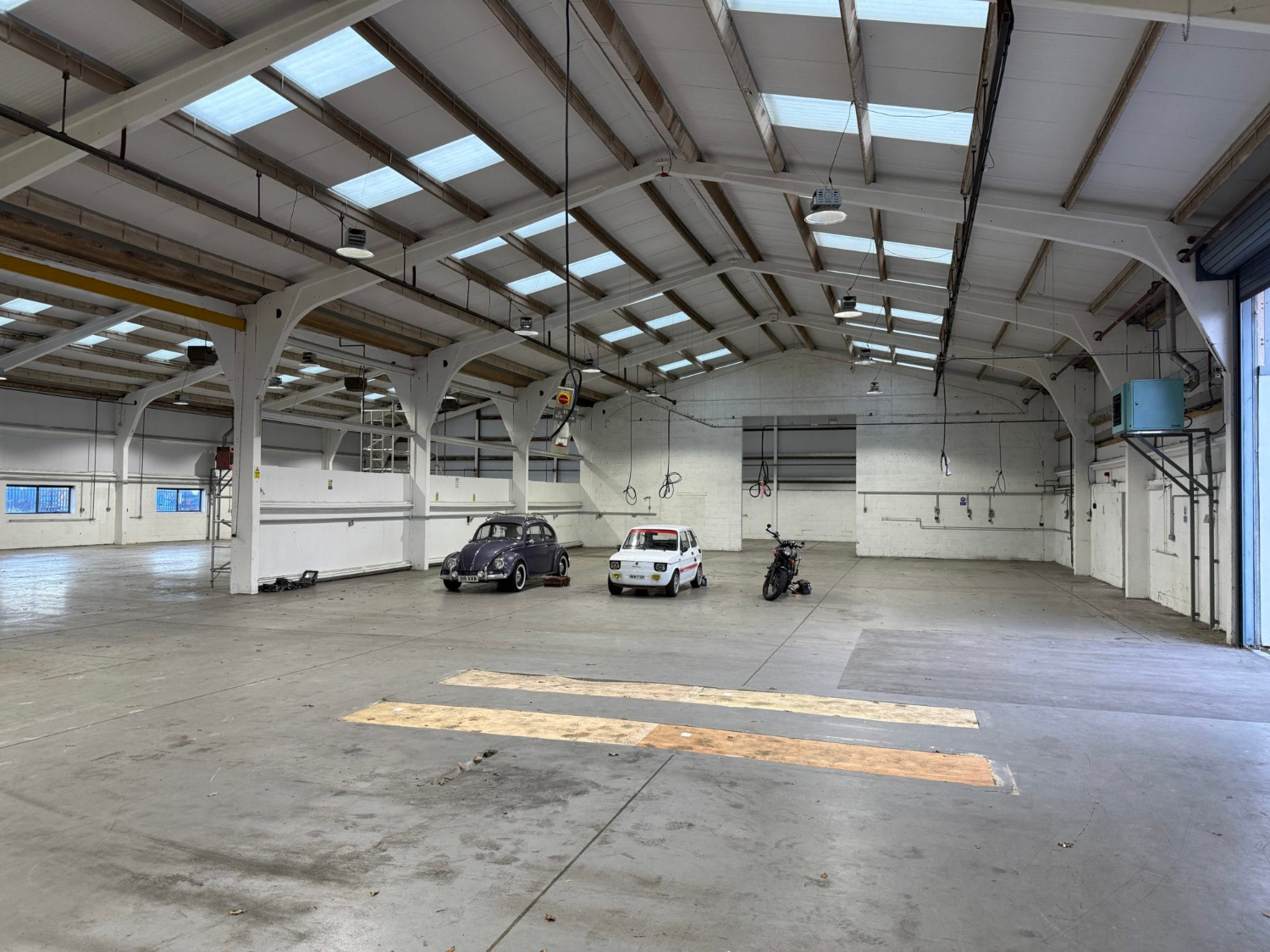 Interior of large industrial warehouse unit showing open floor space, roof structure and building condition during property inspection
