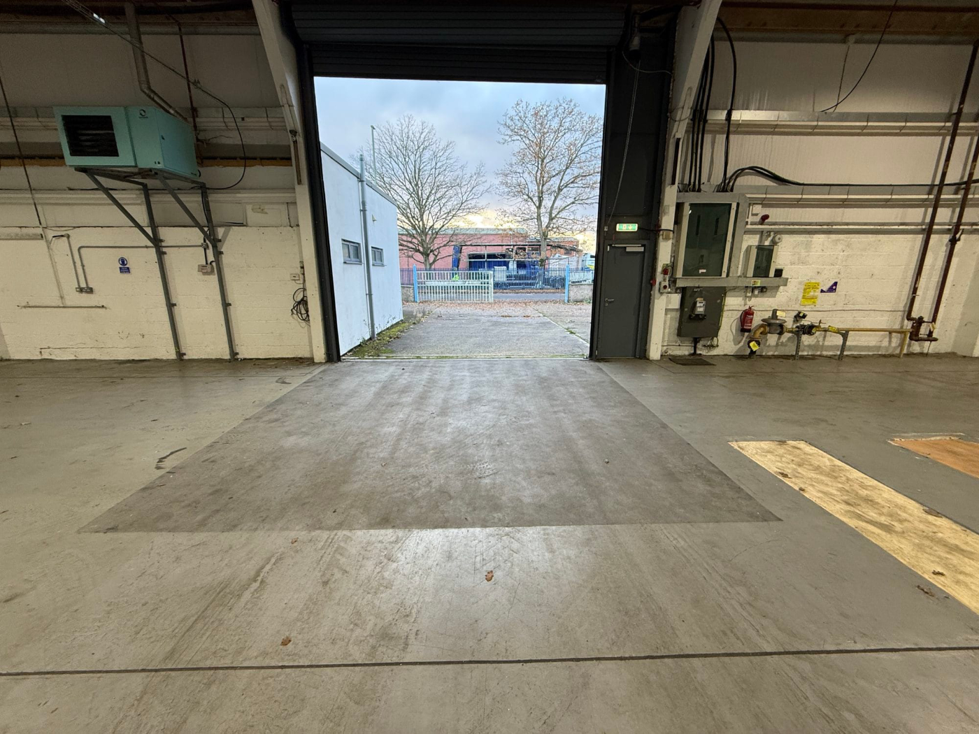 Interior of large industrial warehouse unit Interior of large industrial warehouse unit showing open door and building condition during property inspection