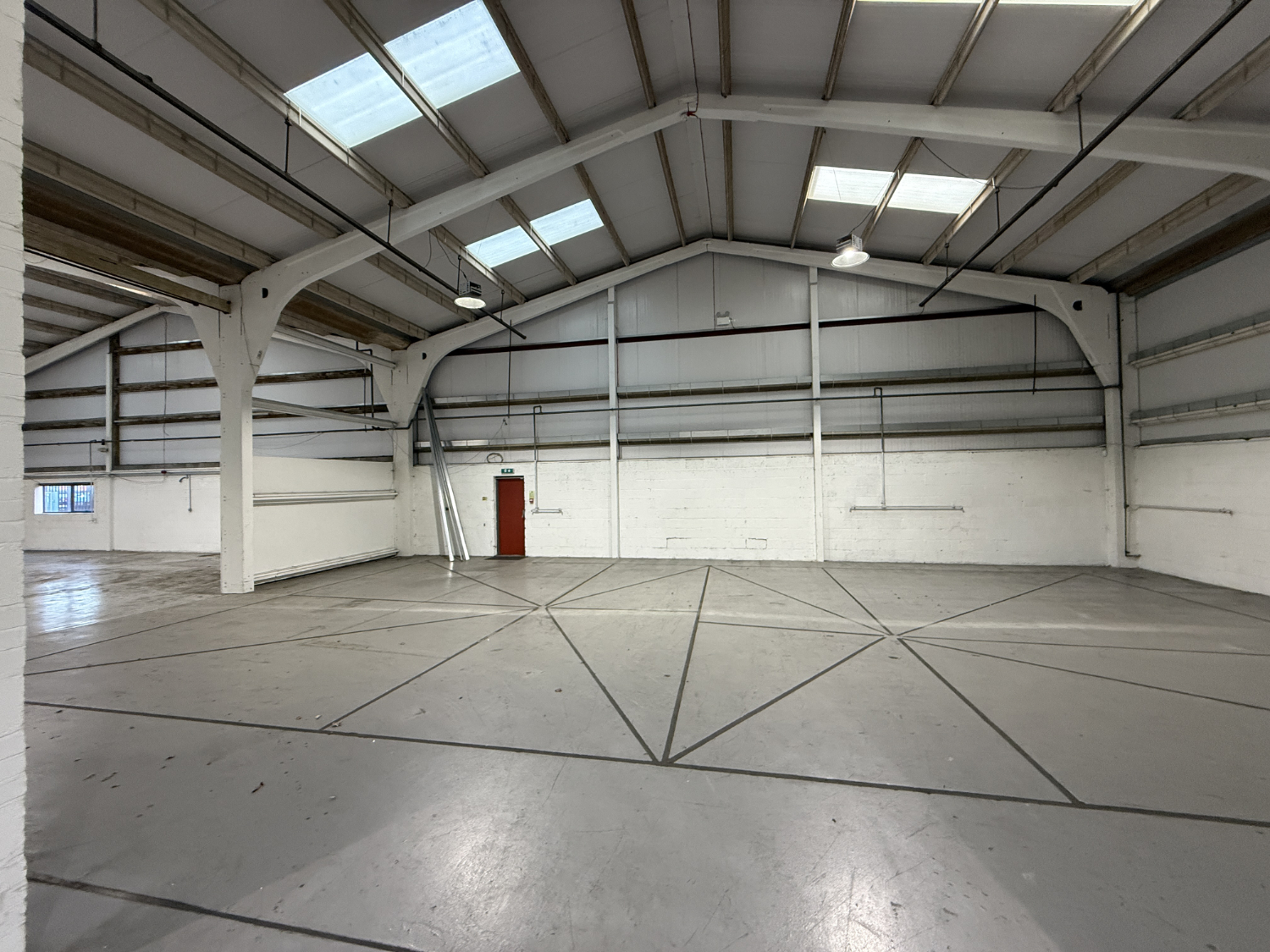 Interior of large industrial warehouse unit showing open floor space, roof structure and building condition during property inspection