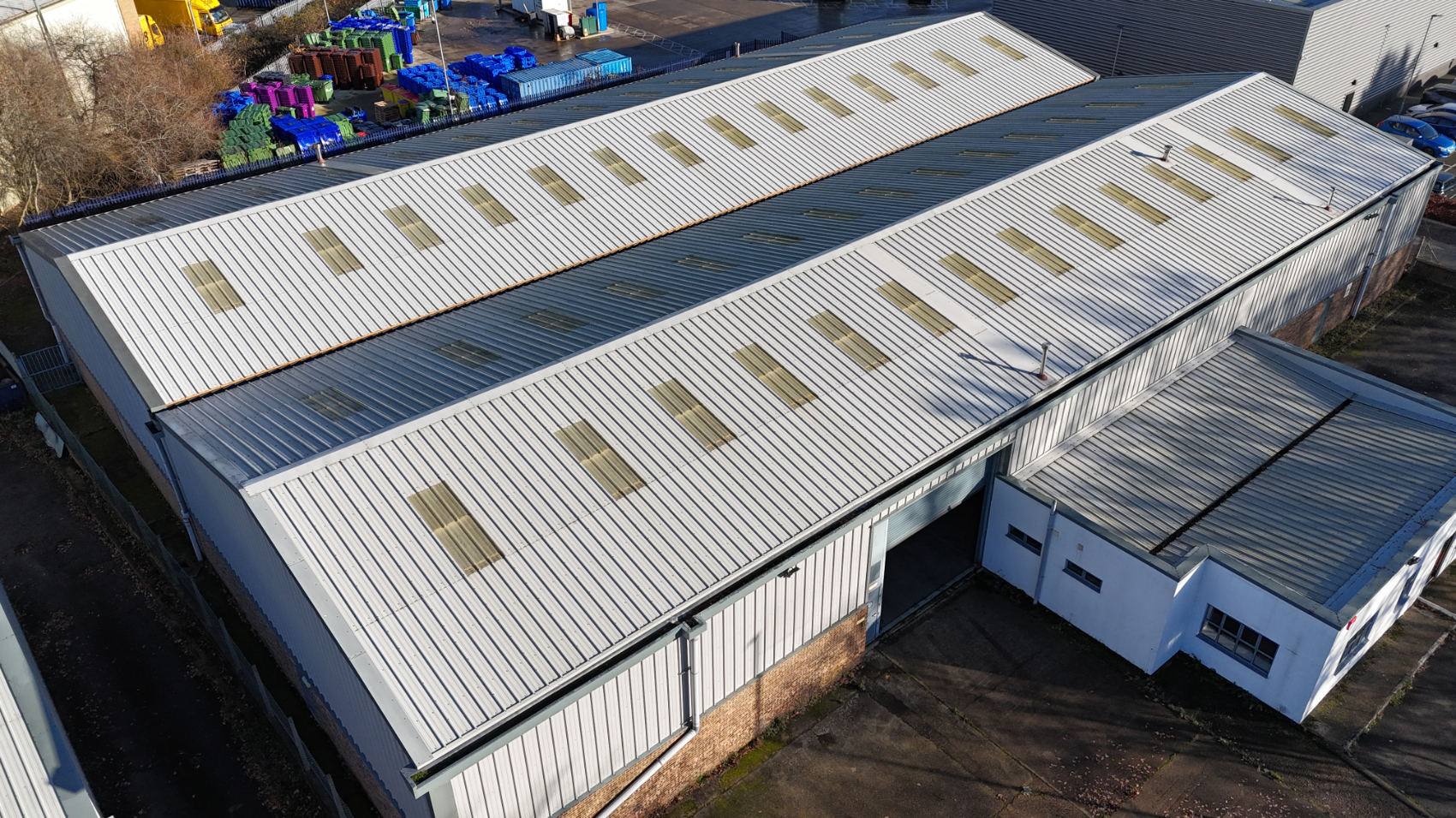 Exterior of large industrial warehouse unit showing roof structure and building condition during property inspection