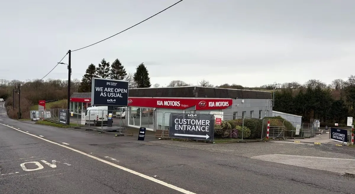 Previous Kia Dealership in Plymouth Drone aerial photograph of previous Kia Plymouth dealership showcasing an old style car showroom and forecourt with heras fencing