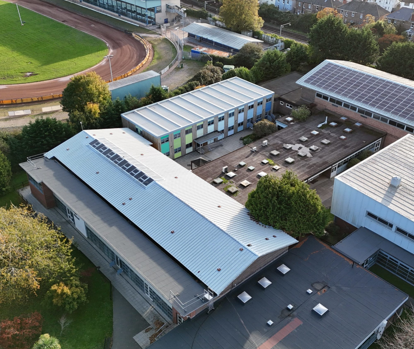 Aerial drone view of school campus building in Poole Dorset and surrounding residential area showing roof layouts and site condition